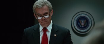 Movie still from “W.” (2008), directed by Oliver Stone – An older man in a suit and red tie; Close Up shot, Low angle