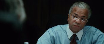 Movie still from “W.” (2008), directed by Oliver Stone – An older man wearing a blue shirt and a red tie; Close Up shot, Over the shoulder angle