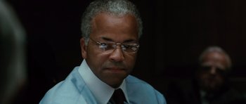 Movie still from “W.” (2008), directed by Oliver Stone – An older man wearing glasses and a shirt and tie; Close Up shot, Low angle