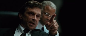 Movie still from “W.” (2008), directed by Oliver Stone – A man in a suit and tie pointing at something; Close Up shot, Over the shoulder angle