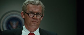 Movie still from “W.” (2008), directed by Oliver Stone – An older man wearing a suit and red tie; Close Up shot, Low angle