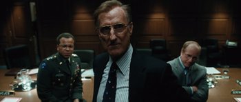 Movie still from “W.” (2008), directed by Oliver Stone – An older man wearing a suit and tie in a courtroom; Medium shot, Low angle
