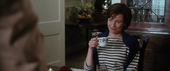 Movie still from “W.” (2008), directed by Oliver Stone – A woman sitting at a table holding a coffee cup; Medium shot, Over the shoulder angle