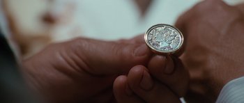 Movie still from “W.” (2008), directed by Oliver Stone – A person is holding a coin in their hand; Extreme Close Up shot, Overhead angle