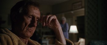 Movie still from “W.” (2008), directed by Oliver Stone – An older man is holding his hand up to his face; Close Up shot, Low angle