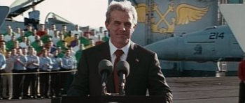 Movie still from “W.” (2008), directed by Oliver Stone – A man standing at a podium with microphones; Medium shot, Low angle