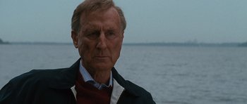 Movie still from “W.” (2008), directed by Oliver Stone – An older man standing in front of a body of water; Close Up shot, Over the shoulder angle