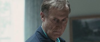 Movie still from “W.” (2008), directed by Oliver Stone – An older man wearing a blue shirt and a blue neck tie; Close Up shot, Low angle