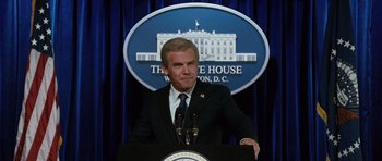 Movie still from “W.” (2008), directed by Oliver Stone – A man in a suit and tie standing at a podium in front of the white house; Close Up shot, Low angle