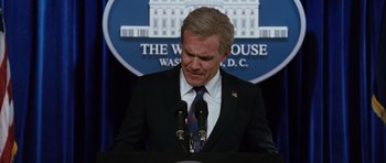 Movie still from “W.” (2008), directed by Oliver Stone – A man standing at a podium in front of microphones; Close Up shot, Low angle