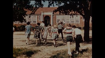 Movie still from “Waiting for Superman” (2010), directed by Davis Guggenheim – A group of people standing in front of a building; Extreme Wide shot, High angle