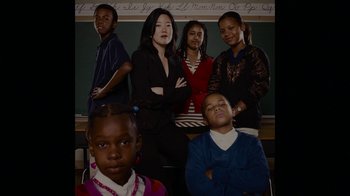 Movie still from “Waiting for Superman” (2010), directed by Davis Guggenheim – A group of people standing next to each other in front of a chalkboard; Medium shot, Low angle