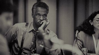 Movie still from “Waiting for Superman” (2010), directed by Davis Guggenheim – An older man is sitting in front of a camera; Close Up shot, Low angle