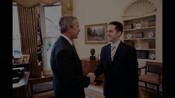 Movie still from “Waiting for Superman” (2010), directed by Davis Guggenheim – Two men in suits shaking hands in front of a window; Medium shot, Over the shoulder angle