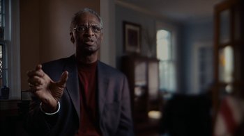 Movie still from “Waiting for Superman” (2010), directed by Davis Guggenheim – An older black man in a suit and red shirt; Close Up shot, Over the shoulder angle