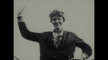 Movie still from “Waiting for Superman” (2010), directed by Davis Guggenheim – An old black and white photo of a woman waving; Medium shot, Low angle
