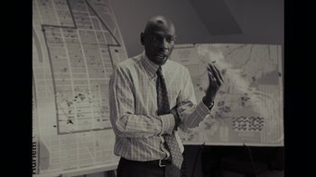 Movie still from “Waiting for Superman” (2010), directed by Davis Guggenheim – A black and white photo of a man wearing a tie; Medium shot, High angle