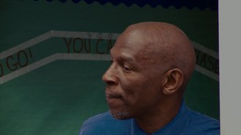 Movie still from “Waiting for Superman” (2010), directed by Davis Guggenheim – An older man with a bald head looking to his left; Close Up shot, Low angle
