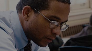 Movie still from “Waiting for Superman” (2010), directed by Davis Guggenheim – A person wearing glasses and a tie; Close Up shot, Low angle