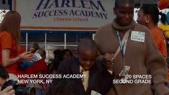 Movie still from “Waiting for Superman” (2010), directed by Davis Guggenheim – A man standing next to a young boy in front of a building; Extreme Wide shot, High angle