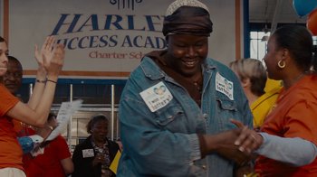 Movie still from “Waiting for Superman” (2010), directed by Davis Guggenheim – An older woman wearing a jean jacket and a hat; Medium shot, Over the shoulder angle