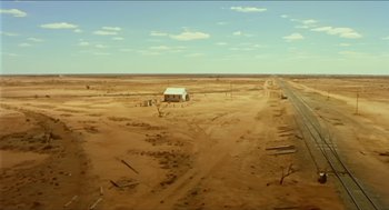Movie still from “Wake in Fright” (1971), directed by Ted Kotcheff – An empty dirt field with a small house in the middle of it; Extreme Wide shot, High angle