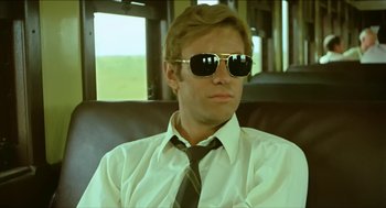 Movie still from “Wake in Fright” (1971), directed by Ted Kotcheff – A man wearing sunglasses sitting in a chair; Close Up shot, Low angle