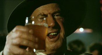 Movie still from “Wake in Fright” (1971), directed by Ted Kotcheff – An old man holding a glass of beer in his hand; Extreme Close Up shot, Low angle