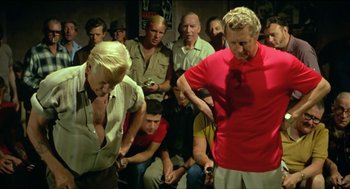 Movie still from “Wake in Fright” (1971), directed by Ted Kotcheff – A group of people sitting in a room; Medium shot, Over the shoulder angle