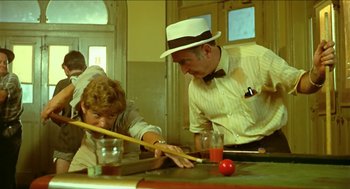Movie still from “Wake in Fright” (1971), directed by Ted Kotcheff – A man in a white hat is playing pool with another man; Medium shot, Over the shoulder angle