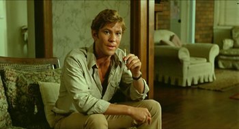 Movie still from “Wake in Fright” (1971), directed by Ted Kotcheff – A man sitting on the ground in a room; Medium shot, Low angle