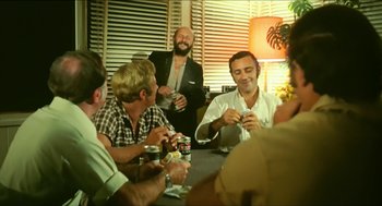 Movie still from “Wake in Fright” (1971), directed by Ted Kotcheff – A group of men sitting at a table drinking beer; Medium shot, Low angle