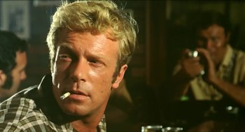 Movie still from “Wake in Fright” (1971), directed by Ted Kotcheff – A person smoking a cigarette; Close Up shot, Over the shoulder angle