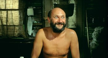 Movie still from “Wake in Fright” (1971), directed by Ted Kotcheff – A man with a beard and a bald head is smiling; Medium shot, Low angle