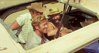Movie still from “Wake in Fright” (1971), directed by Ted Kotcheff – A group of men sitting in the back of a truck; Medium shot, Over the shoulder angle