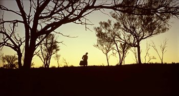 Movie still from “Wake in Fright” (1971), directed by Ted Kotcheff – A person sitting on top of a grass covered field; Extreme Wide shot, Low angle