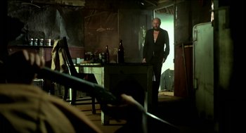 Movie still from “Wake in Fright” (1971), directed by Ted Kotcheff – A man standing in front of a table in a dark room; Wide shot, Low angle