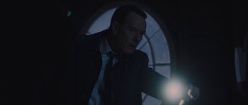 Movie still from “Wakefield” (2016), directed by Robin Swicord – A man wearing a suit and tie pointing at something in the dark; Close Up shot, Low angle