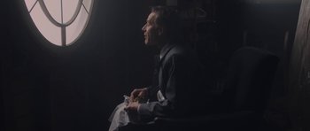 Movie still from “Wakefield” (2016), directed by Robin Swicord – A man sitting in front of a window holding a glass of wine; Medium shot, Over the shoulder angle
