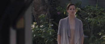 Movie still from “Wakefield” (2016), directed by Robin Swicord – A woman standing in front of a tree and bushes; Medium shot, Over the shoulder angle
