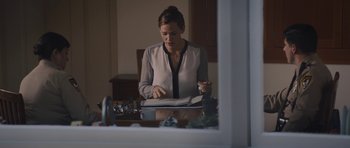 Movie still from “Wakefield” (2016), directed by Robin Swicord – A woman sitting at a dining room table looking at a book; Medium shot, Over the shoulder angle