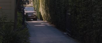 Movie still from “Wakefield” (2016), directed by Robin Swicord – A car parked on the side of the road near a fence; Wide shot, High angle