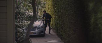 Movie still from “Wakefield” (2016), directed by Robin Swicord – A man standing next to a silver car on the side of the road; Wide shot, High angle