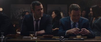 Movie still from “Wakefield” (2016), directed by Robin Swicord – Two men sitting at a table in front of a woman; Medium shot, Over the shoulder angle