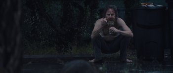 Movie still from “Wakefield” (2016), directed by Robin Swicord – A man squatting on the ground eating food; Medium shot, Low angle