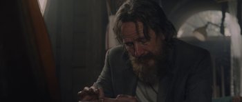 Movie still from “Wakefield” (2016), directed by Robin Swicord – A man with long hair and a goatee sitting at a table; Close Up shot, Over the shoulder angle