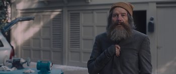 Movie still from “Wakefield” (2016), directed by Robin Swicord – An old man with a long gray beard is standing in front of a building; Medium shot, Over the shoulder angle