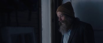 Movie still from “Wakefield” (2016), directed by Robin Swicord – An old man with a beard wearing a hat looking out of a window; Close Up shot, Over the shoulder angle
