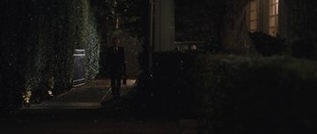 Movie still from “Wakefield” (2016), directed by Robin Swicord – A man in a suit and tie standing on the steps of a house; Extreme Wide shot, Over the shoulder angle
