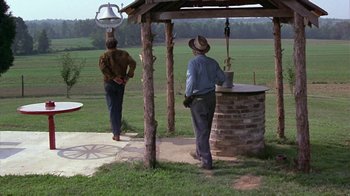 Movie still from “Walking Tall” (1973), directed by Phil Karlson – Two men standing in front of an outdoor structure; Wide shot, Over the shoulder angle
